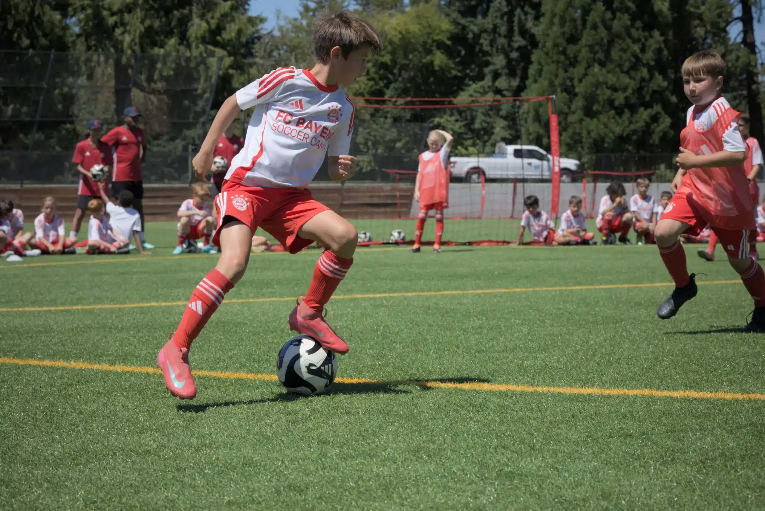 Young players train on a turf field under sunny skies, hoping for a successful turn during their local soccer club tryouts.